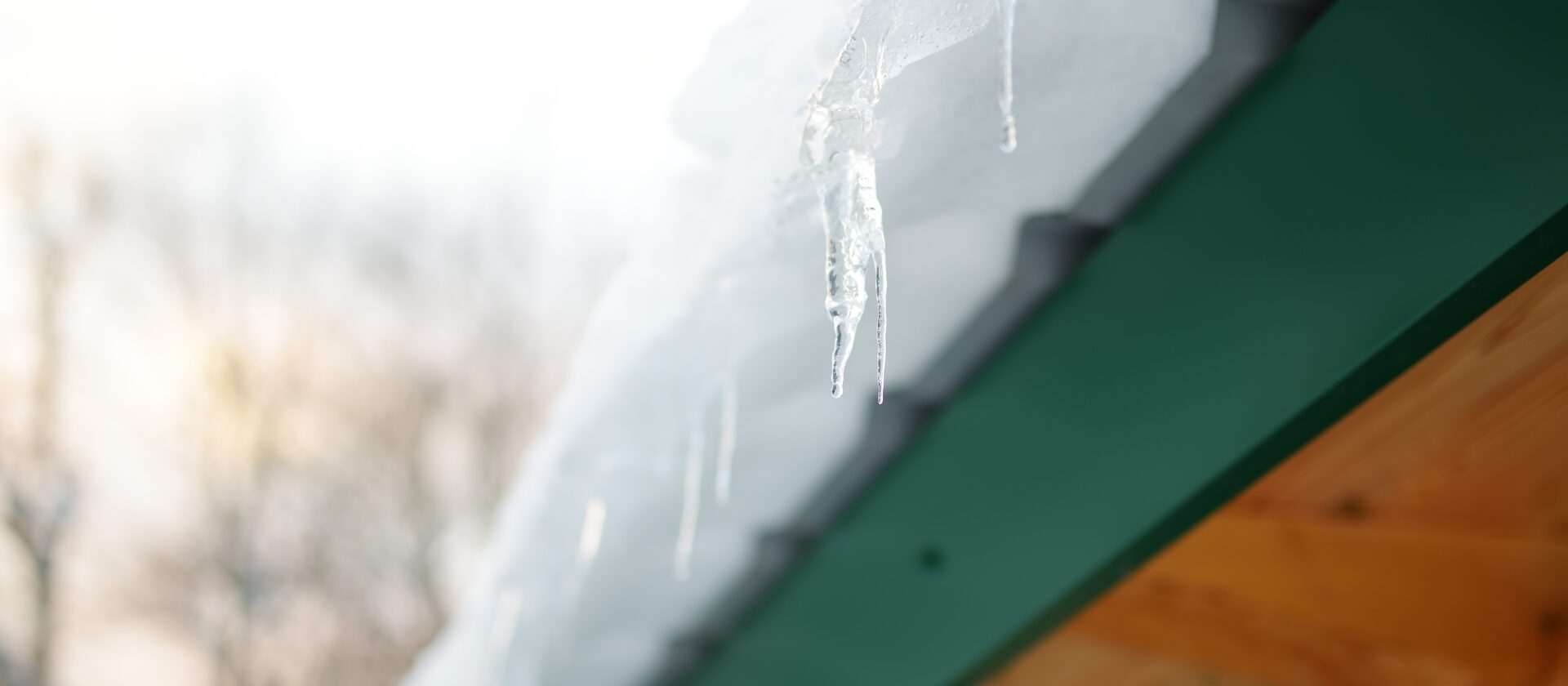 The roof of a house on a snowy winter day among thaw. Cleaning the roofing from snow and icicles. Danger of snowy season.