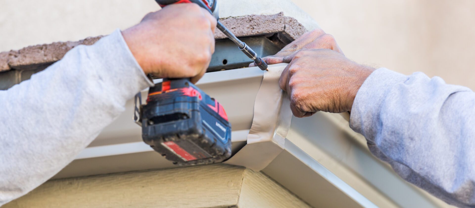 Workers Attaching Aluminum Rain Gutter to Fascia of House.